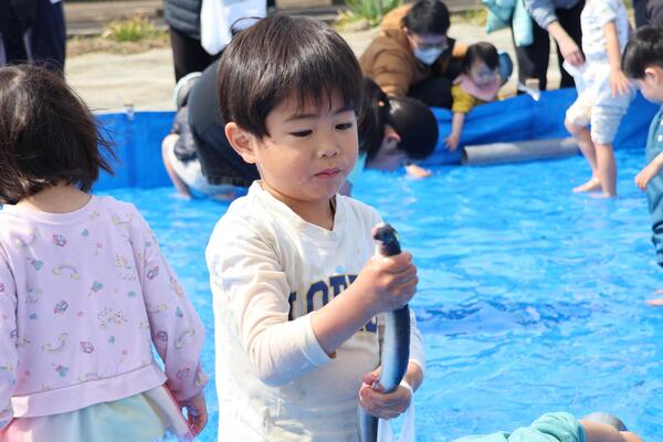 菜の花まつりでうなぎを取りをする子どもの写真